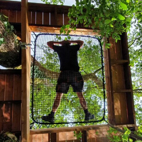 Homme suspendu dans un filet de terrasse perchée