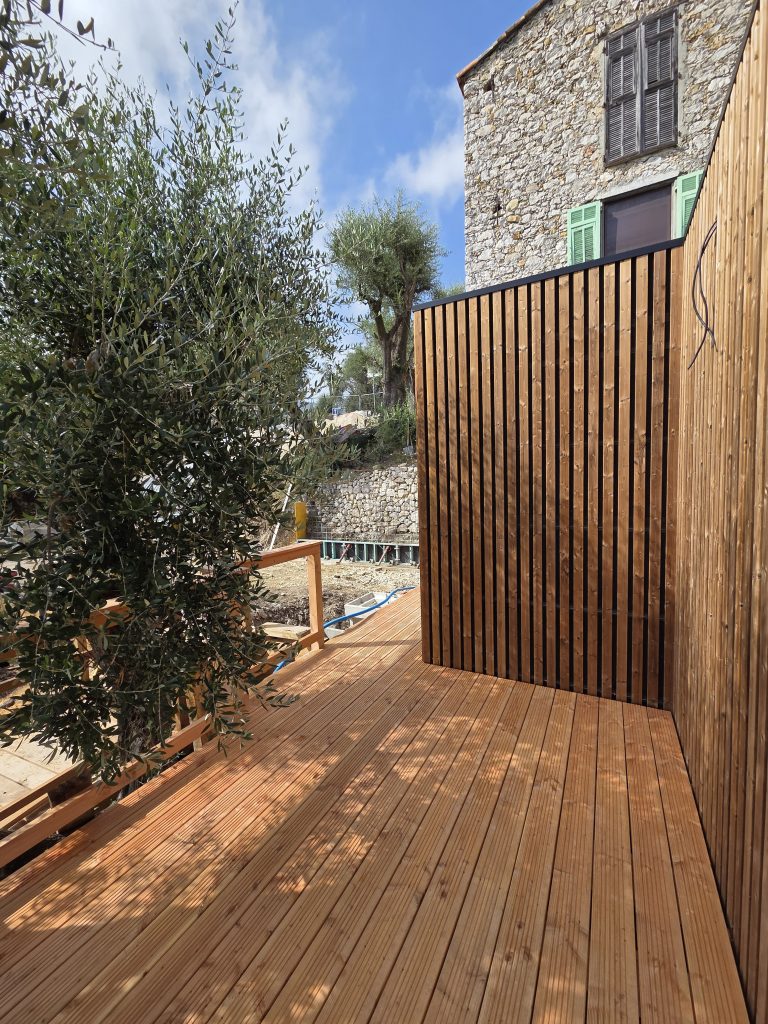 Bardage bois du cabanon et terrasse entourée d’oliviers