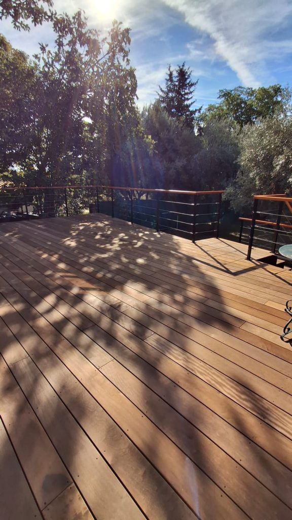 Lames de terrasse en itauba au soleil, entourées de végétation
